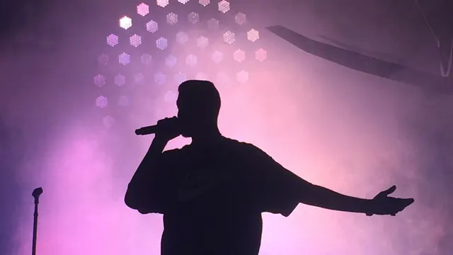 Orelsan à Paris : chanteur en silhouette au micro sur scène